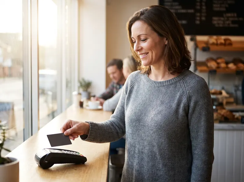 A woman tapping her card to pay at a cafe